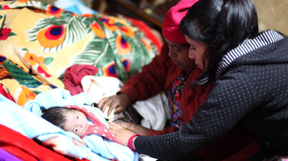 Partera y comadrona tradicional atienden a una mujer y su recién nacido en Totonicapán